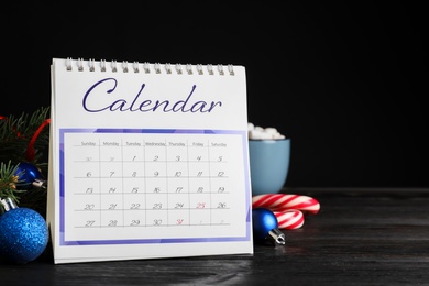 Photo of Flip calendar and Christmas decor on black wooden table. Holiday countdown