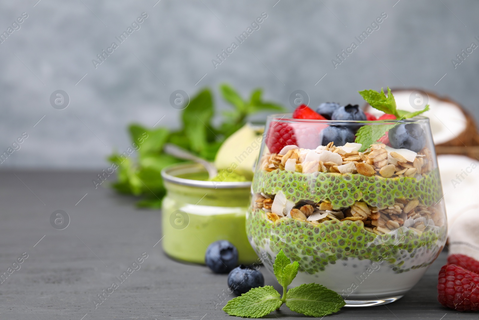 Photo of Tasty oatmeal with chia matcha pudding and berries on black wooden table, closeup. Space for text. Healthy breakfast