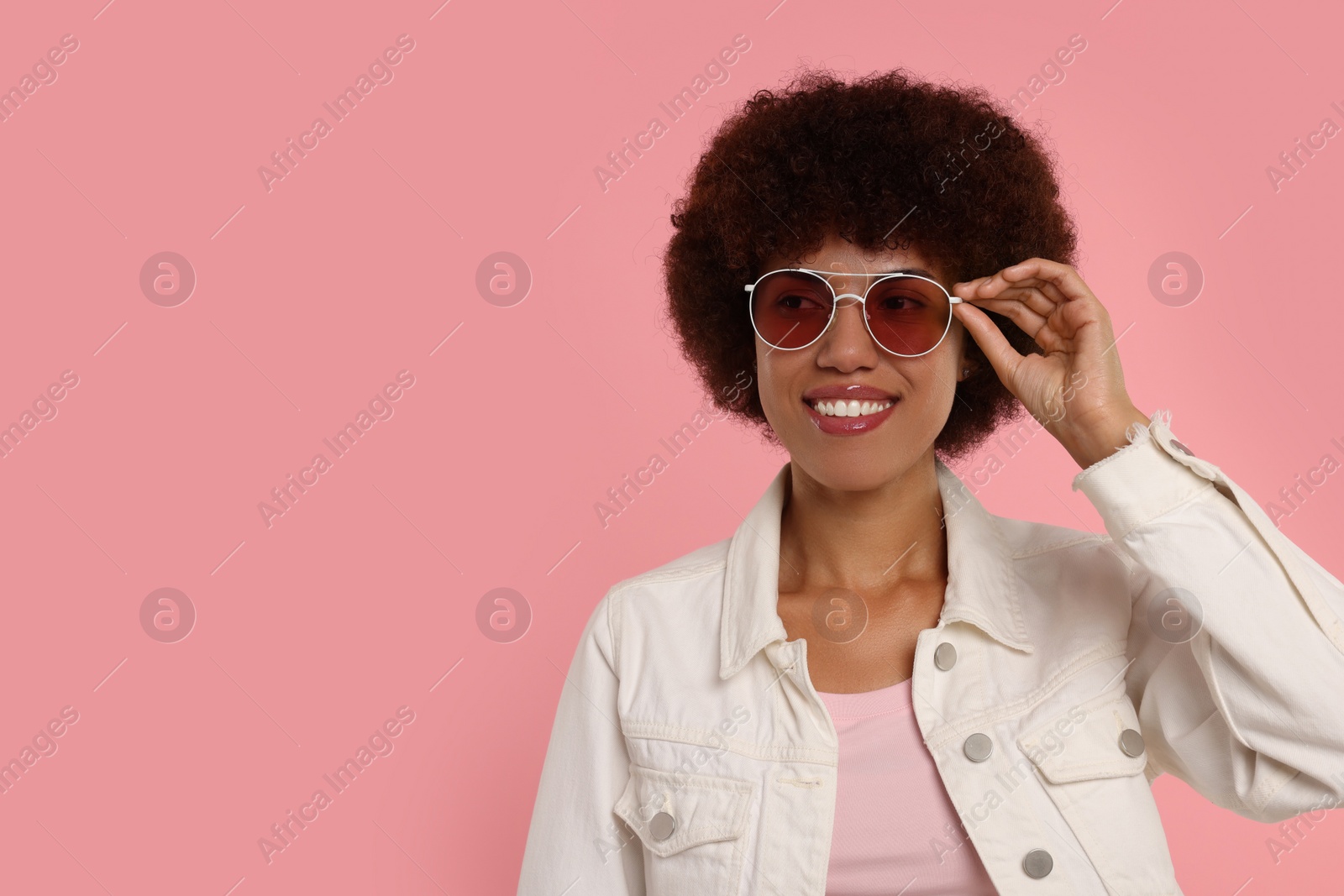 Photo of Portrait of young woman in sunglasses on pink background. Space for text