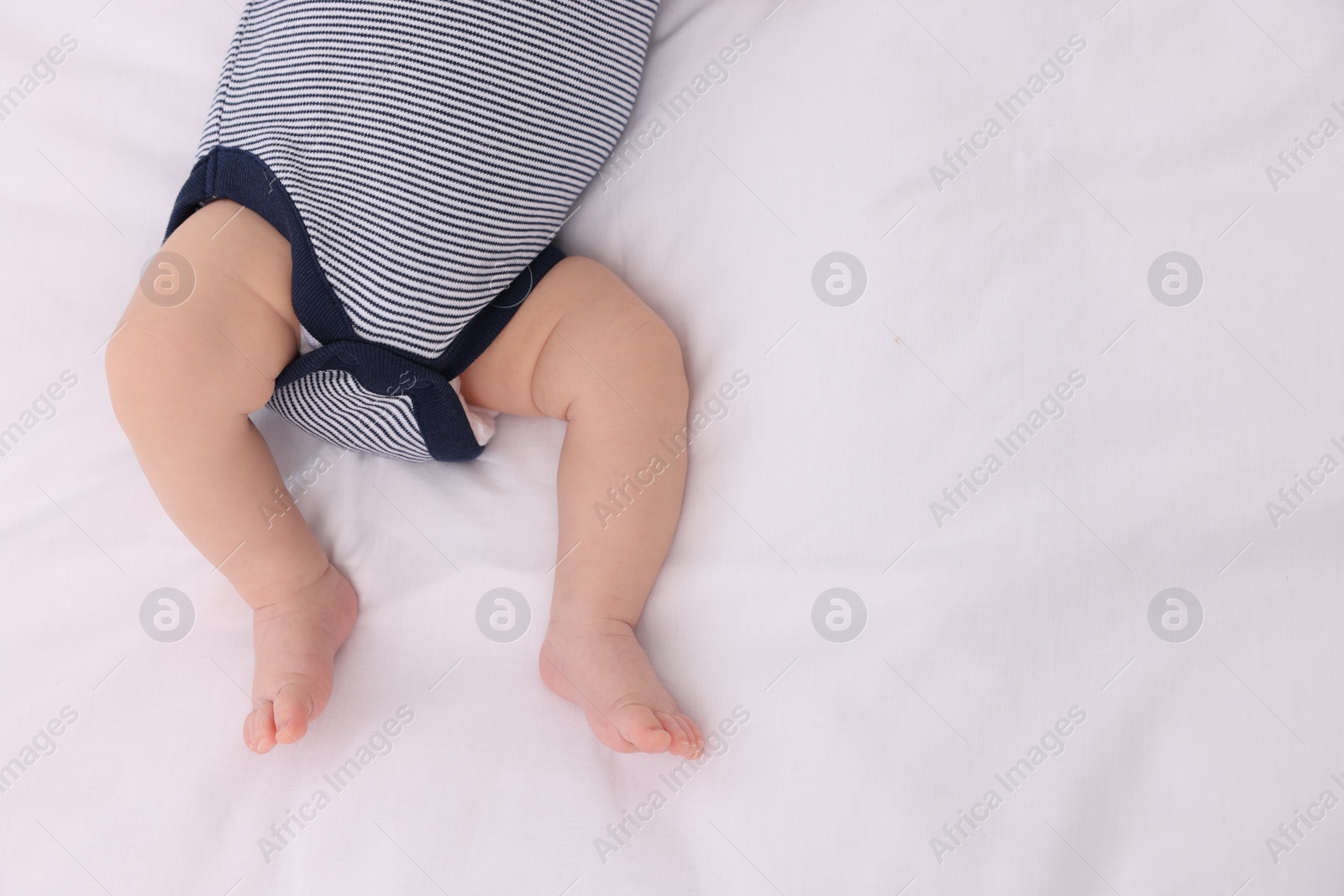 Photo of Newborn baby lying on white blanket, top view. Space for text