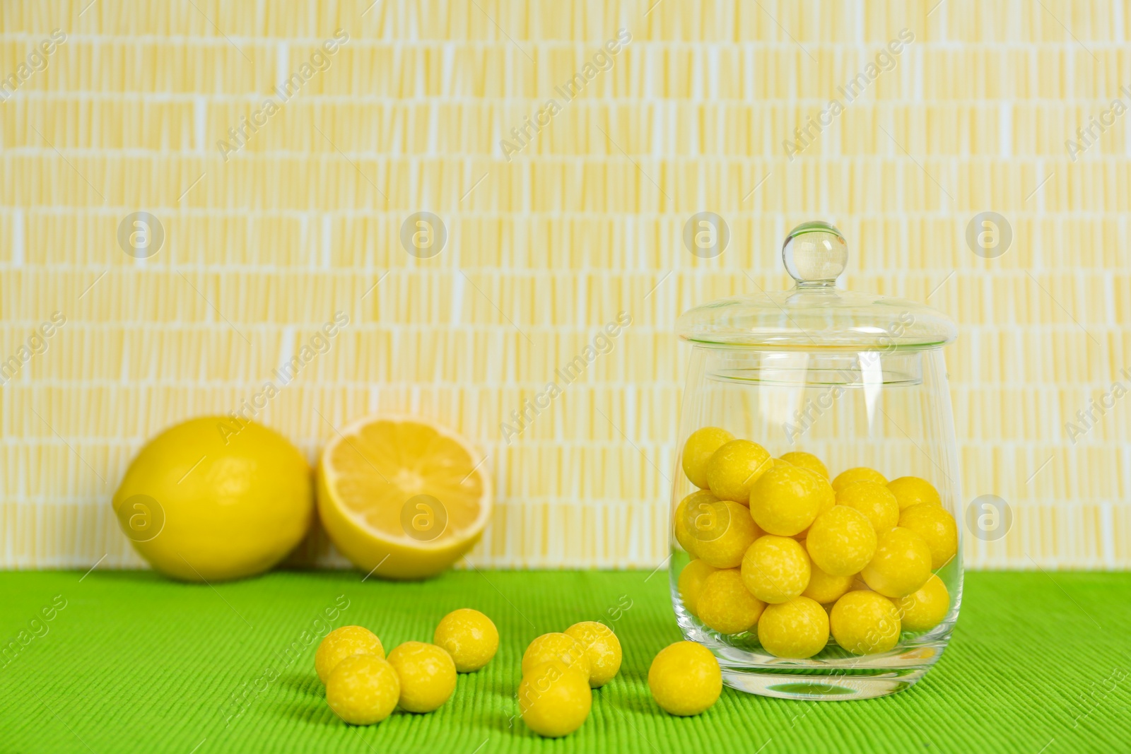 Photo of Delicious lemon drops on green tablecloth. Space for text