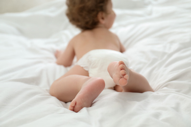 Cute little baby in diaper on bed