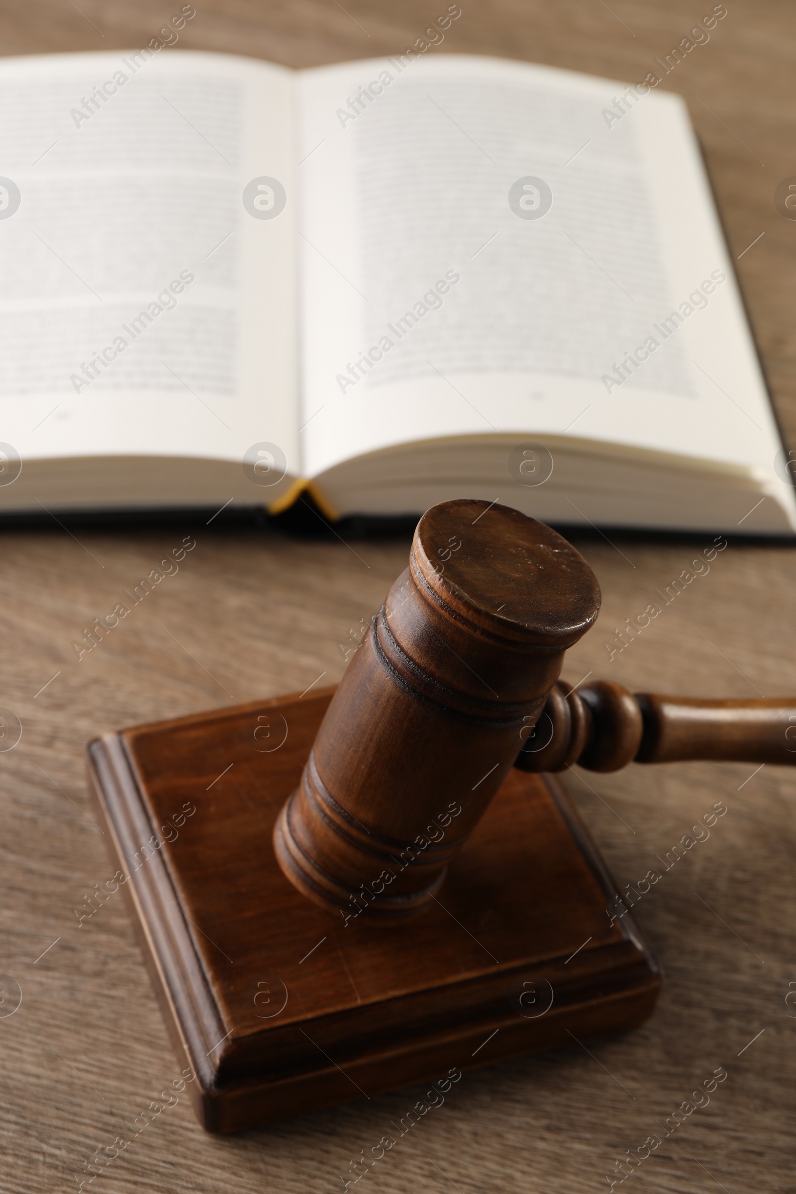 Photo of Law concept. Mallet and open book on wooden table, closeup