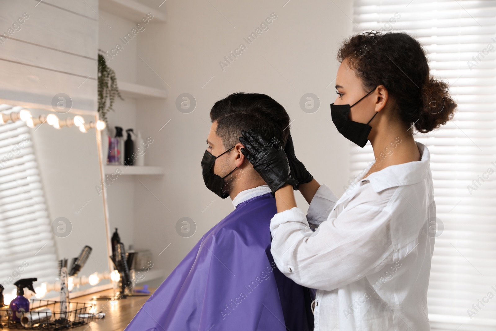 Photo of Professional stylist working with client in salon. Hairdressing services during Coronavirus quarantine