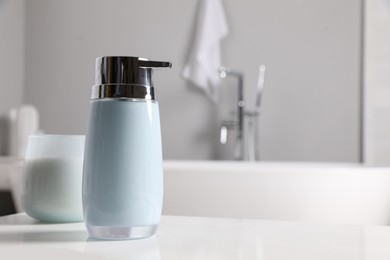 Dispenser of liquid soap on white table in bathroom, space for text