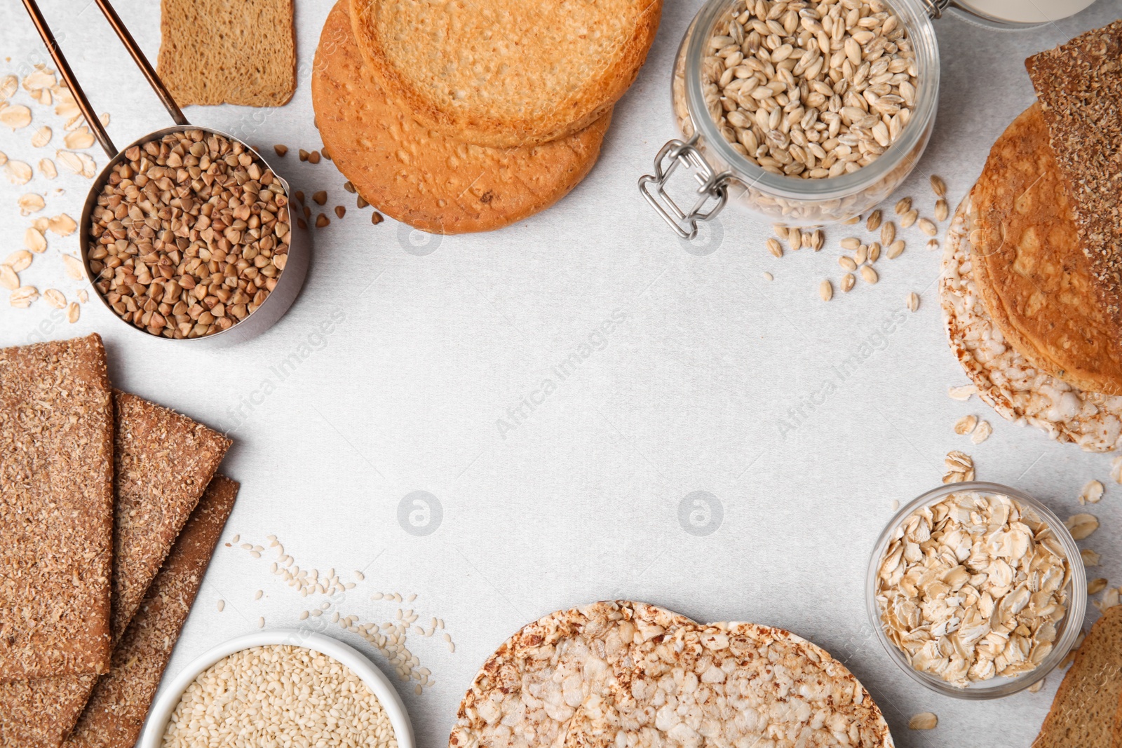 Photo of Frame of rye crispbreads, rice cakes and rusks on white table, flat lay. Space for text