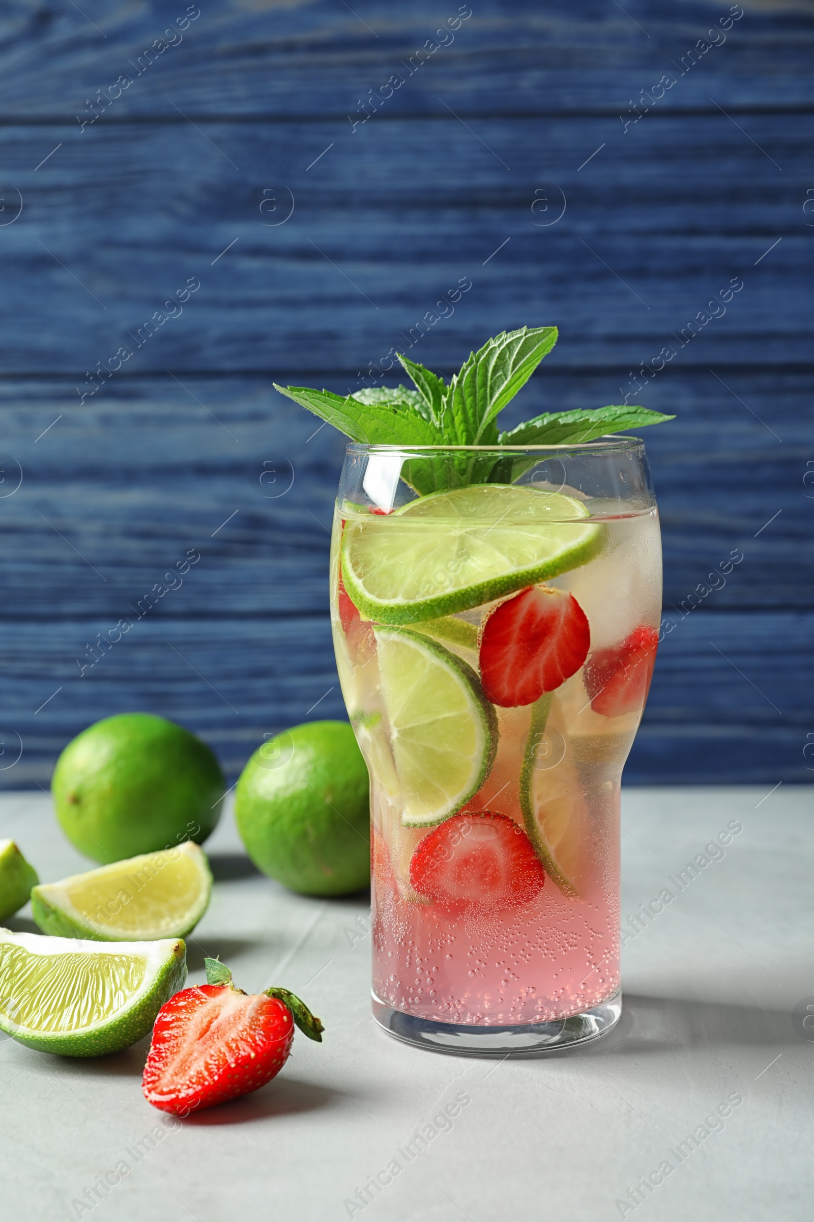 Photo of Natural lemonade with lime and strawberries in glass on table