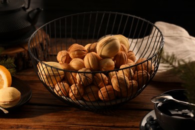 Photo of Aromatic walnut shaped cookies with tasty filling and tea on wooden table. Homemade pastry carrying nostalgic atmosphere