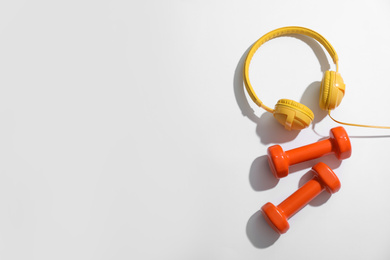 Photo of Dumbbells and headphones on white background, top view. Physical fitness