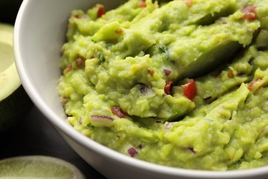 Photo of Bowl of delicious guacamole on table, closeup