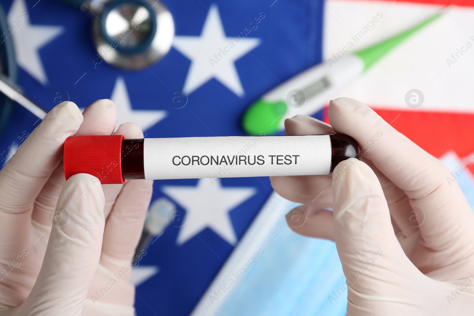 Photo of Scientist holding test tube with blood sample over American flag, closeup. Coronavirus pandemic in USA