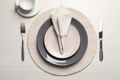 Photo of Plates with fabric napkin, decorative ring and cutlery on white wooden table, flat lay