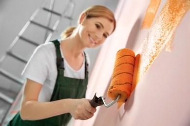 Professional decorator painting wall indoors. Home repair service