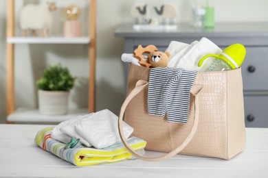 Photo of Mother's bag with baby's stuff on white wooden table indoors