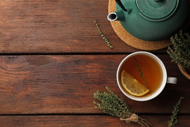 Photo of Aromatic herbal tea with thyme and lemon on wooden table, flat lay. Space for text