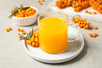 Photo of Delicious sea buckthorn tea and fresh berries on light grey table