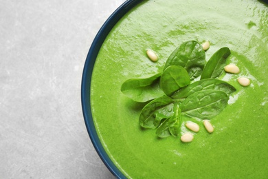 Bowl of healthy green soup with fresh spinach on grey table, top view