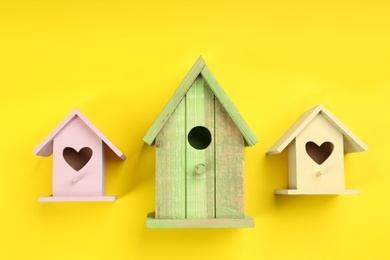 Photo of Beautiful bird houses on yellow background, flat lay