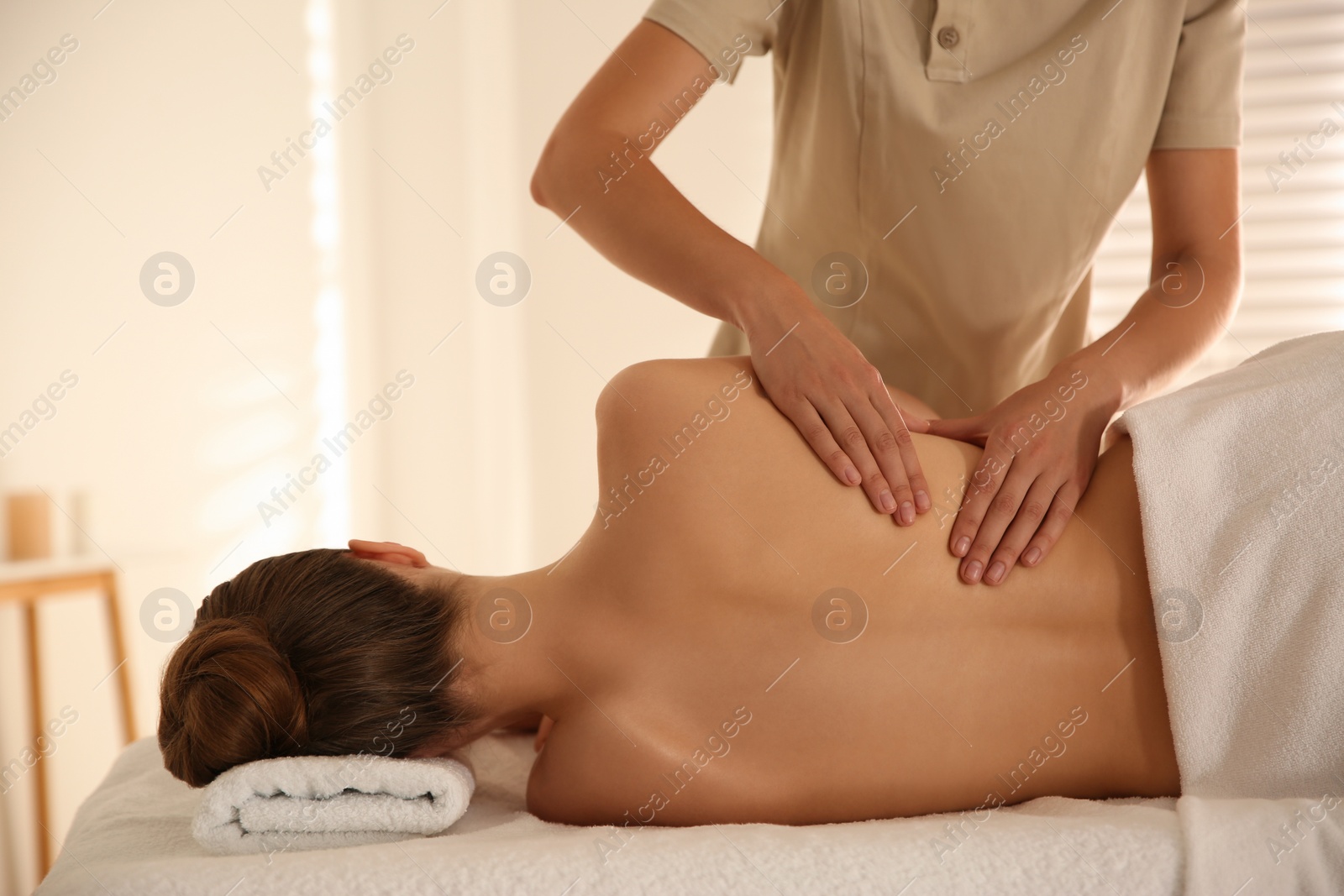 Photo of Young woman receiving back massage in spa salon