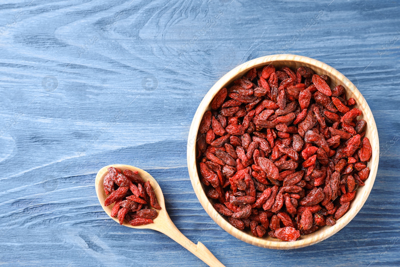 Photo of Dry goji berries on blue wooden table, flat lay