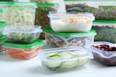 Photo of Set of plastic containers with fresh food on white wooden table
