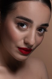 Portrait of beautiful young woman with red lips on brown background, closeup