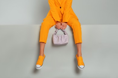 Image of Young woman wearing stylish orange clothes with bag on grey background, closeup