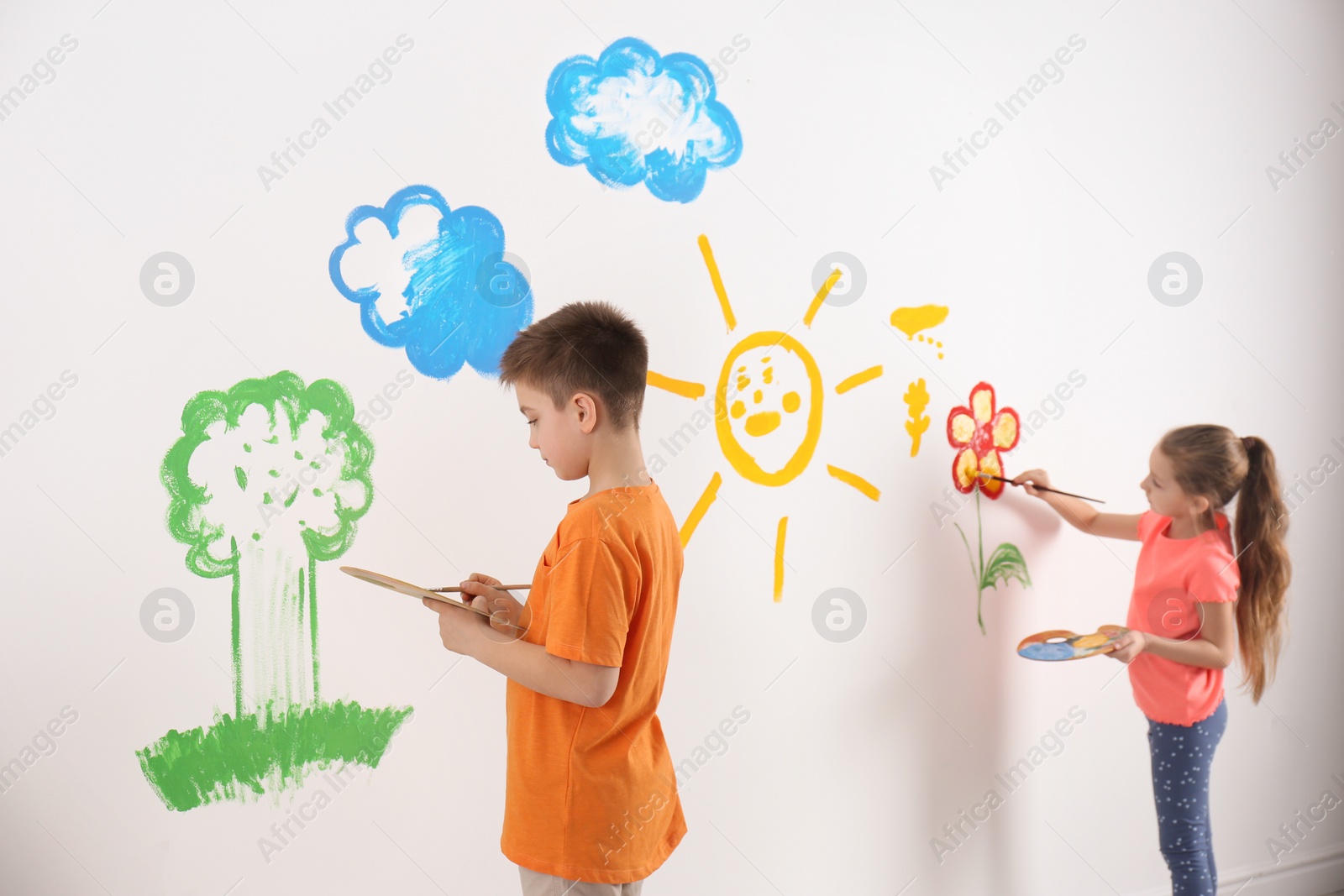 Photo of Little children painting on white wall indoors