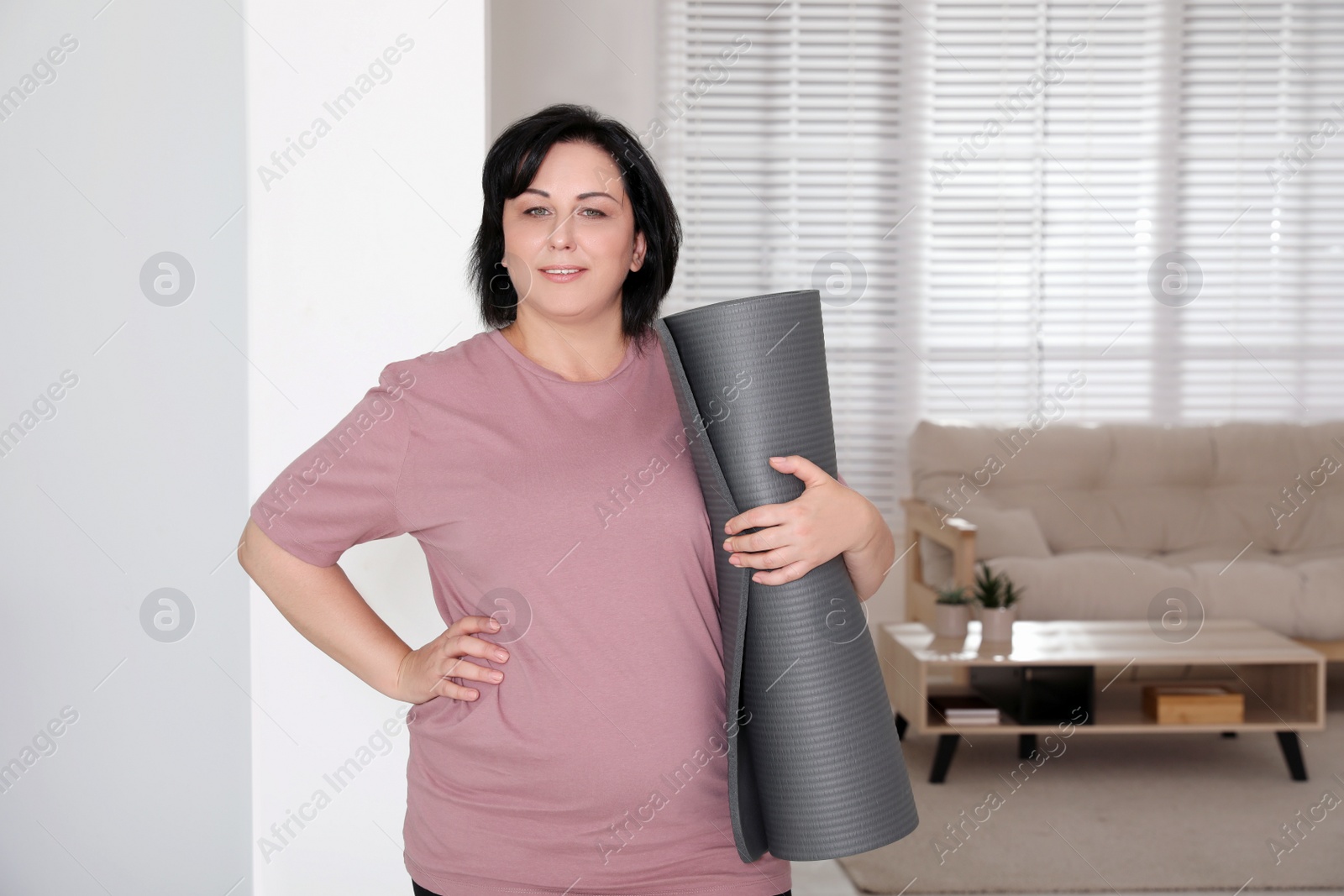 Photo of Overweight mature woman with yoga mat at home