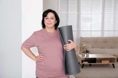 Overweight mature woman with yoga mat at home