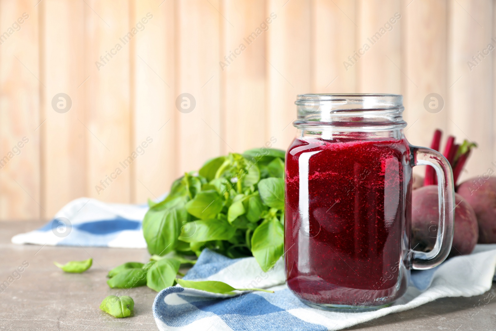 Photo of Mason jar with fresh beet juice and ingredients on table