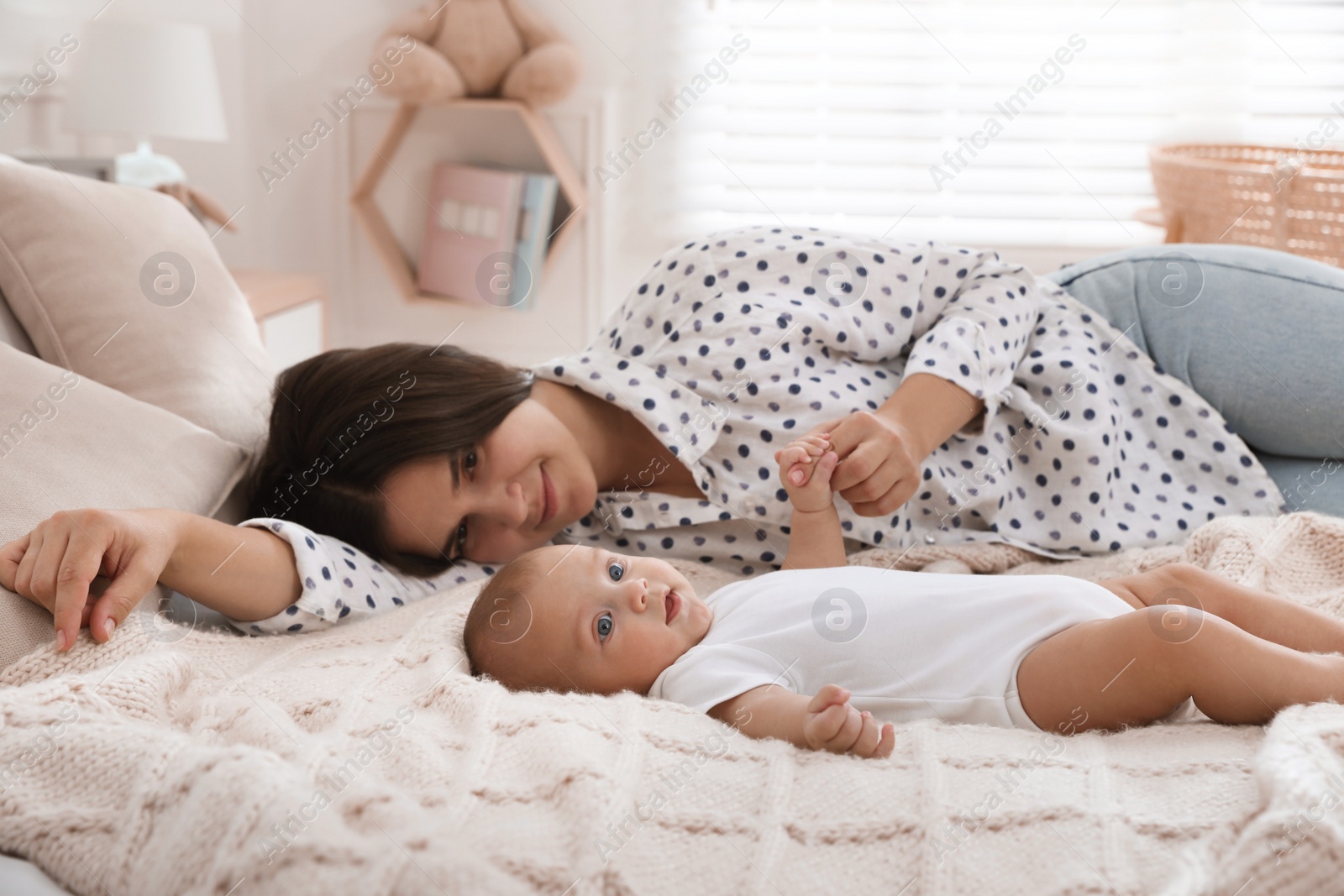 Photo of Mother with her cute baby on bed at home