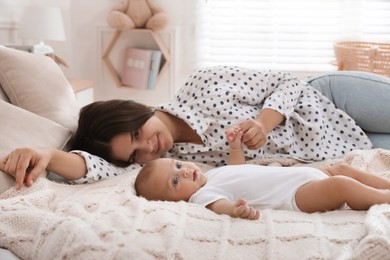 Mother with her cute baby on bed at home