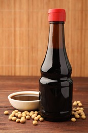 Photo of Soy sauce and soybeans on wooden table