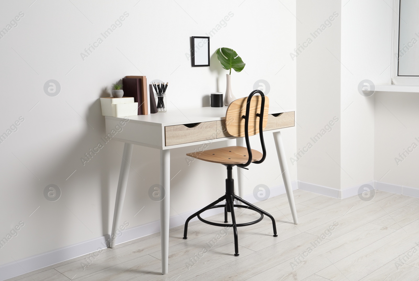 Photo of Comfortable workplace with white desk near wall indoors