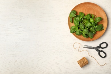 Photo of Plate with fresh basil leaves on wooden background, top view. Space for text