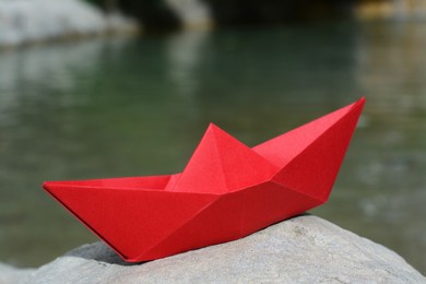 Photo of Beautiful red paper boat on stone outdoors, closeup