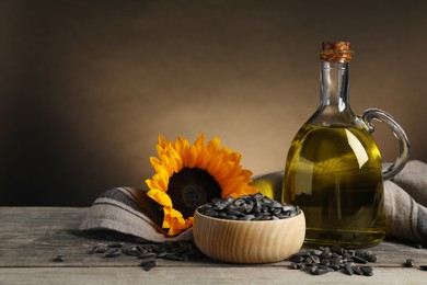 Sunflower cooking oil, seeds and yellow flower on light grey table, space for text