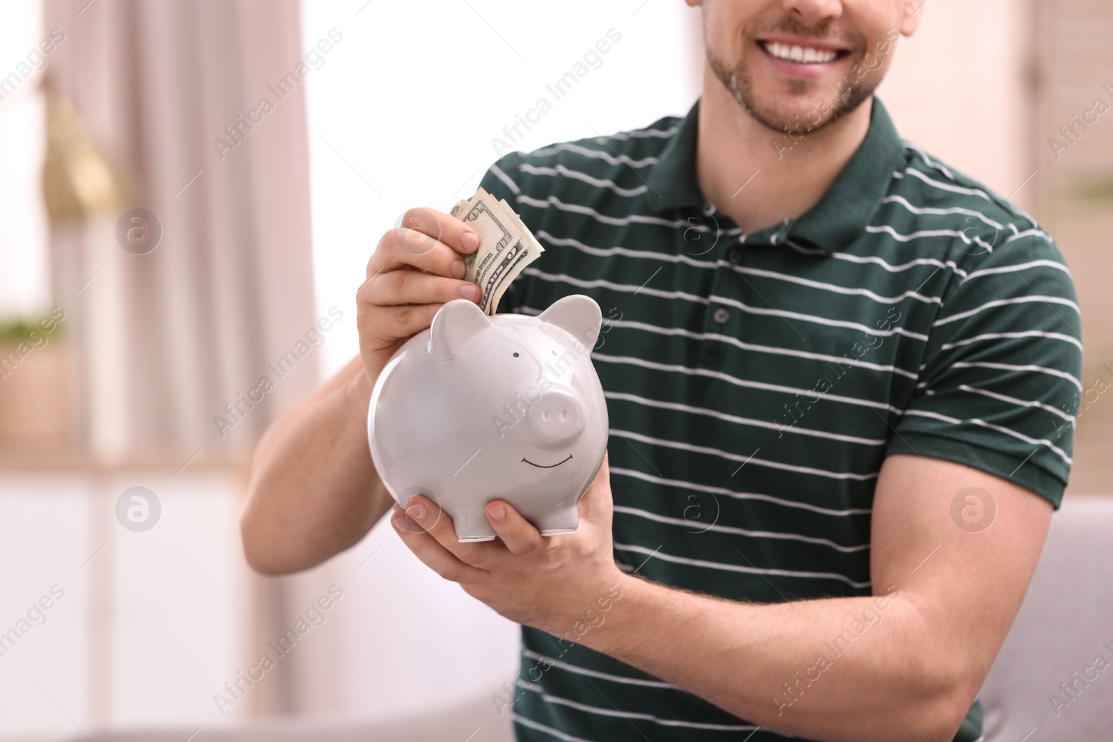 Photo of Man with piggy bank and money at home