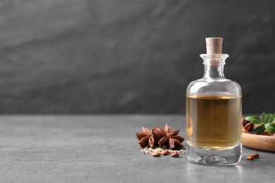 Anise essential oil and spices on grey table, space for text