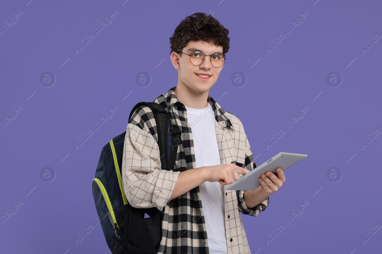 Photo of Portrait of student with backpack and tablet on purple background