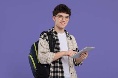 Portrait of student with backpack and tablet on purple background