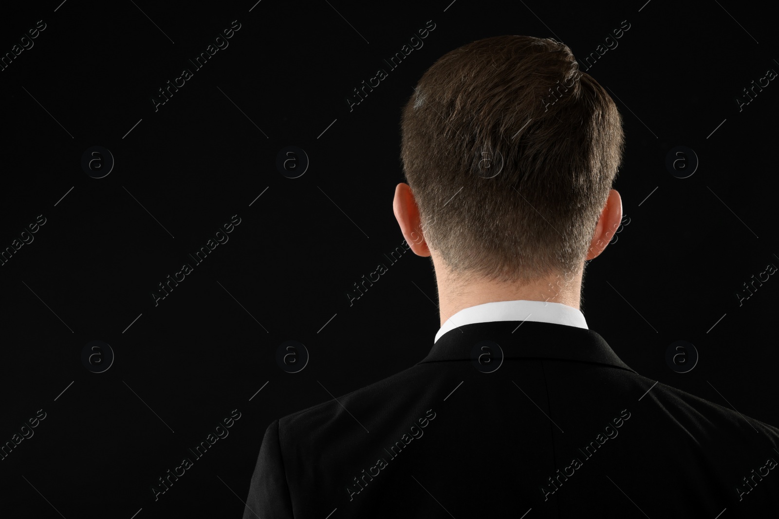 Photo of Man on black background, back view. Space for text