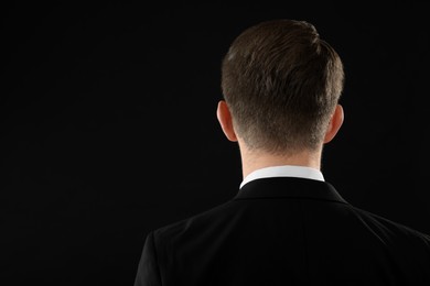 Photo of Man on black background, back view. Space for text