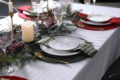 Photo of Christmas table setting with festive decor and dishware