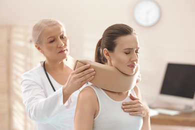 Female orthopedist applying cervical collar onto patient's neck in clinic
