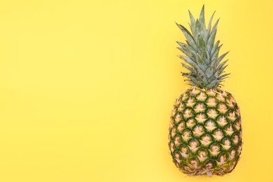 Photo of Delicious ripe pineapple on yellow background, top view. Space for text