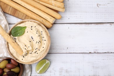 Delicious hummus with grissini sticks served on white wooden table, flat lay. Space for text