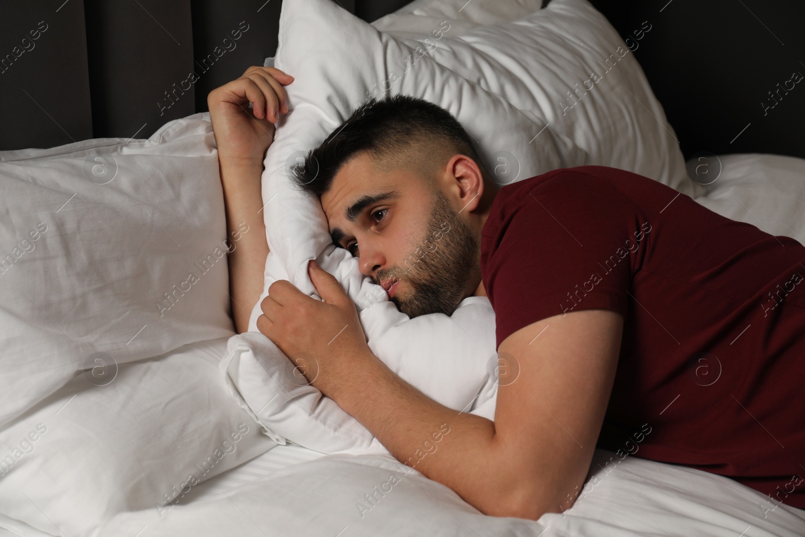 Photo of Sad man lying on bed at home