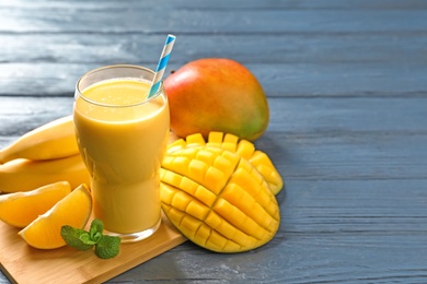 Tasty tropical drink with mango and fresh fruits on wooden table. Space for text